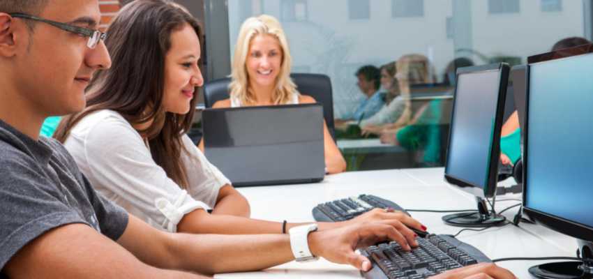 Three employees of a software company working diligently during busy hours.